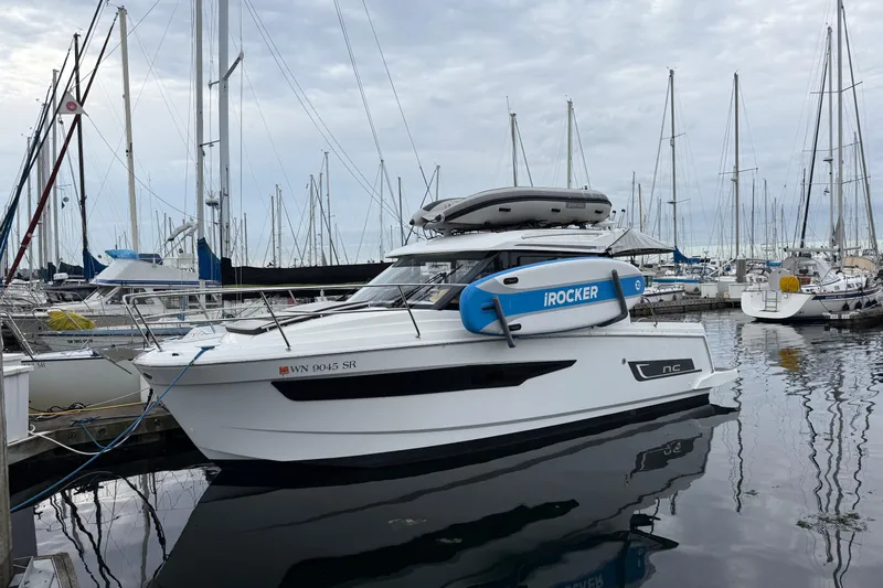  Yacht Photos Pics 2019 Jeanneau NC 895 boat docked at marina with paddleboard and inflatable on top.