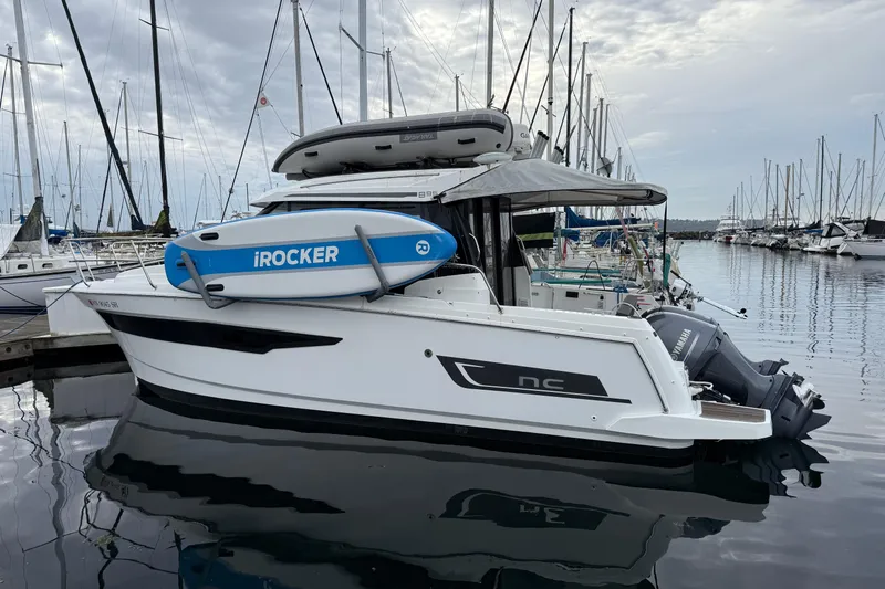  Yacht Photos Pics 2019 Jeanneau NC 895 boat docked with iRocker paddleboard, overcast marina background.