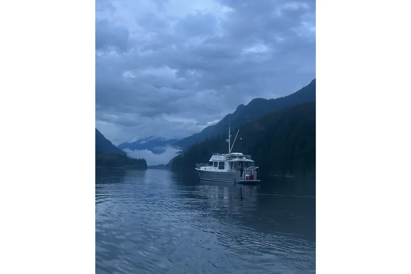 Sante Yacht Photos Pics 2013 Beneteau Swift Trawler 34 Fly on serene lake with mountainous backdrop.