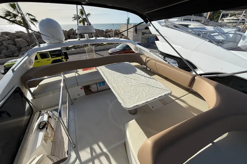  Yacht Photos Pics Flybridge view of 2015 Absolute 56 FLY yacht with seating and table, near ocean.