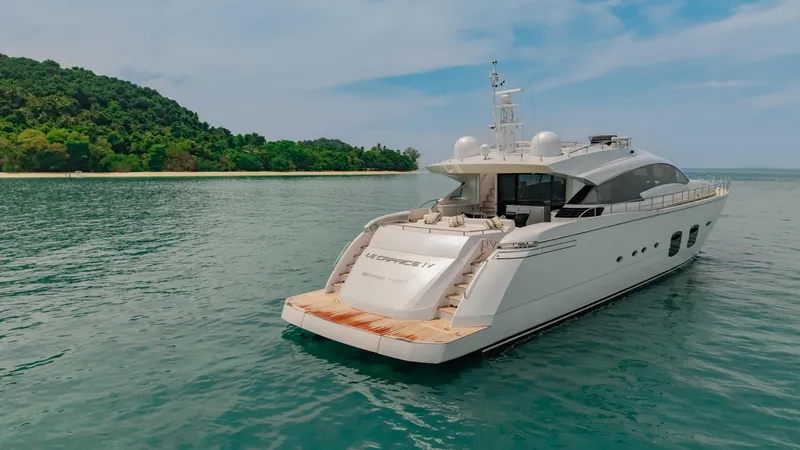 Le Caprice IV Yacht Photos Pics Luxurious 2011 Pershing 108 yacht cruising near a lush, green island.