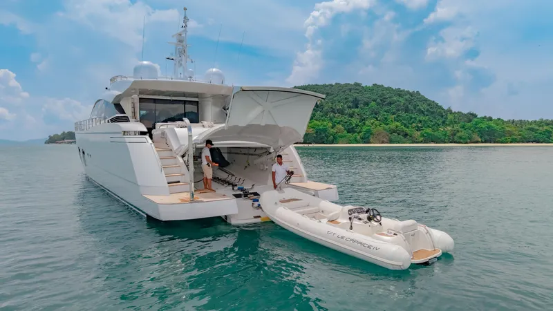 Le Caprice IV Yacht Photos Pics Luxury Pershing 108 yacht with tender, anchored near lush island, under a bright blue sky.
