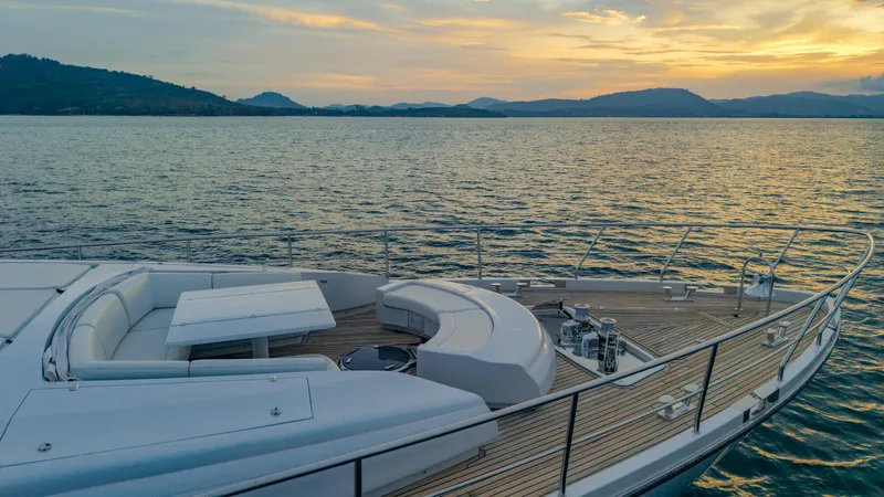 Le Caprice IV Yacht Photos Pics Luxurious 2011 Pershing 108 yacht deck at sunset, overlooking serene waters and distant hills.