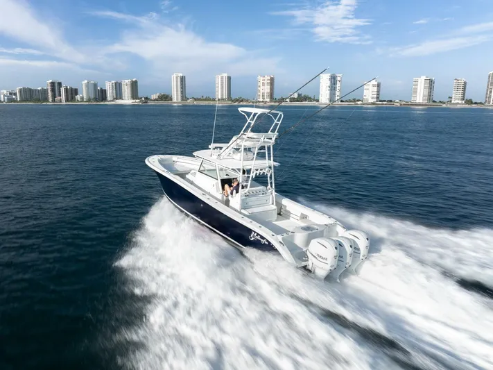  Yacht Photos Pics 2016 Yellowfin 42 boat cruising near city skyline on open water.