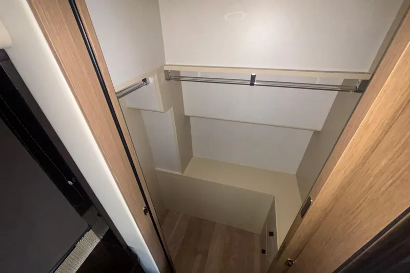  Yacht Photos Pics Spacious closet interior in 2023 Absolute 60 Fly yacht, featuring wooden finishes and hanging rod.