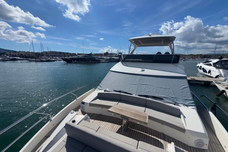  Yacht Photos Pics 2023 Absolute 60 Fly yacht docked in a sunny marina, showcasing luxury seating and sleek design.