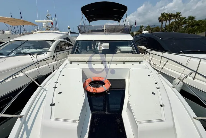  Yacht Photos Pics 2022 Galeon 460 Fly yacht docked, featuring spacious deck and lifebuoy, surrounded by other boats.