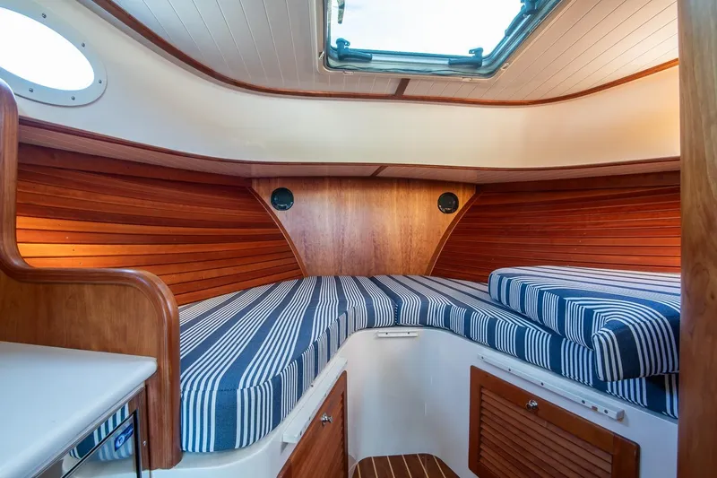 Glory Yacht Photos Pics 2013 Hinckley Talaria 34 cabin interior with striped cushions and wooden paneling.