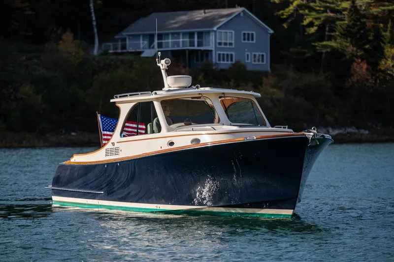 Glory Yacht Photos Pics 2013 Hinckley Talaria 34 boat on serene water with a house in the background.