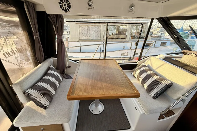  Yacht Photos Pics Interior of 2022 Jeanneau NC Weekender 895 with cozy seating and wooden table.