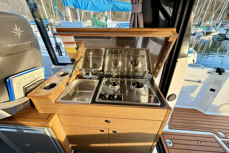  Yacht Photos Pics 2022 Jeanneau NC Weekender 895 boat kitchen with stove and sink, docked at marina.