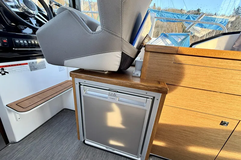  Yacht Photos Pics Interior of 2022 Jeanneau NC Weekender 895 with helm seat and compact fridge.