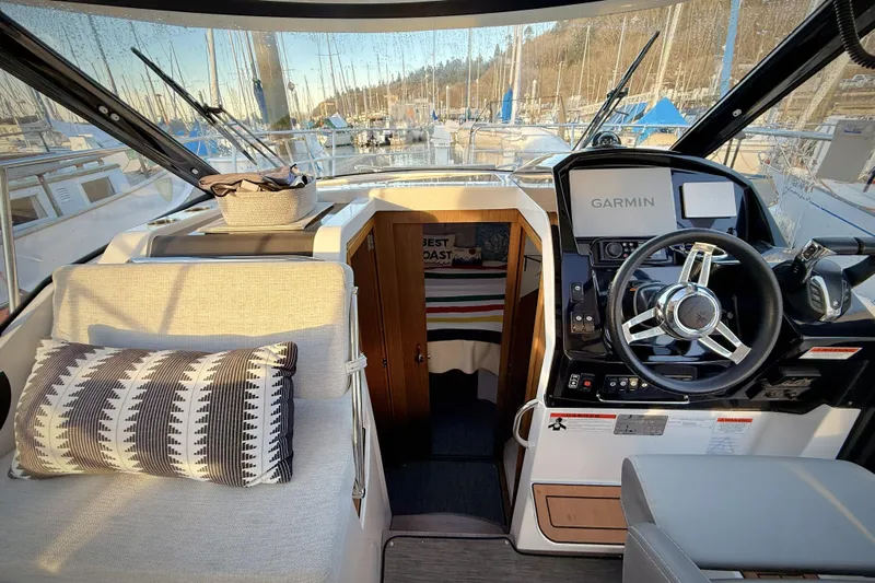  Yacht Photos Pics Interior of 2022 Jeanneau NC Weekender 895 with steering wheel and Garmin navigation system.