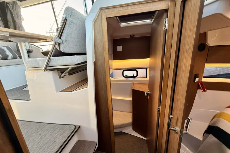  Yacht Photos Pics Interior of 2022 Jeanneau NC Weekender 895, featuring cozy seating and wooden finishes.