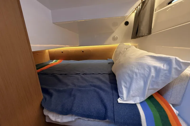  Yacht Photos Pics Cozy cabin interior of 2022 Jeanneau NC Weekender 895 with colorful bedding.