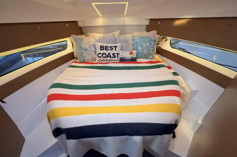  Yacht Photos Pics Cozy cabin interior of 2022 Jeanneau NC Weekender 895 with colorful bedding and decorative pillows.