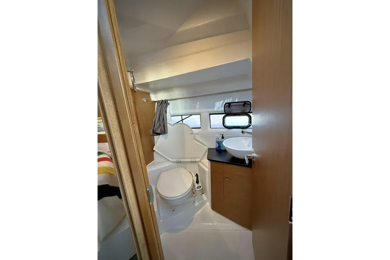  Yacht Photos Pics Compact bathroom in 2022 Jeanneau NC Weekender 895 boat, featuring toilet and sink.