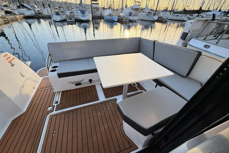  Yacht Photos Pics Jeanneau NC Weekender 895, 2022 model, featuring a cozy outdoor seating area with table.