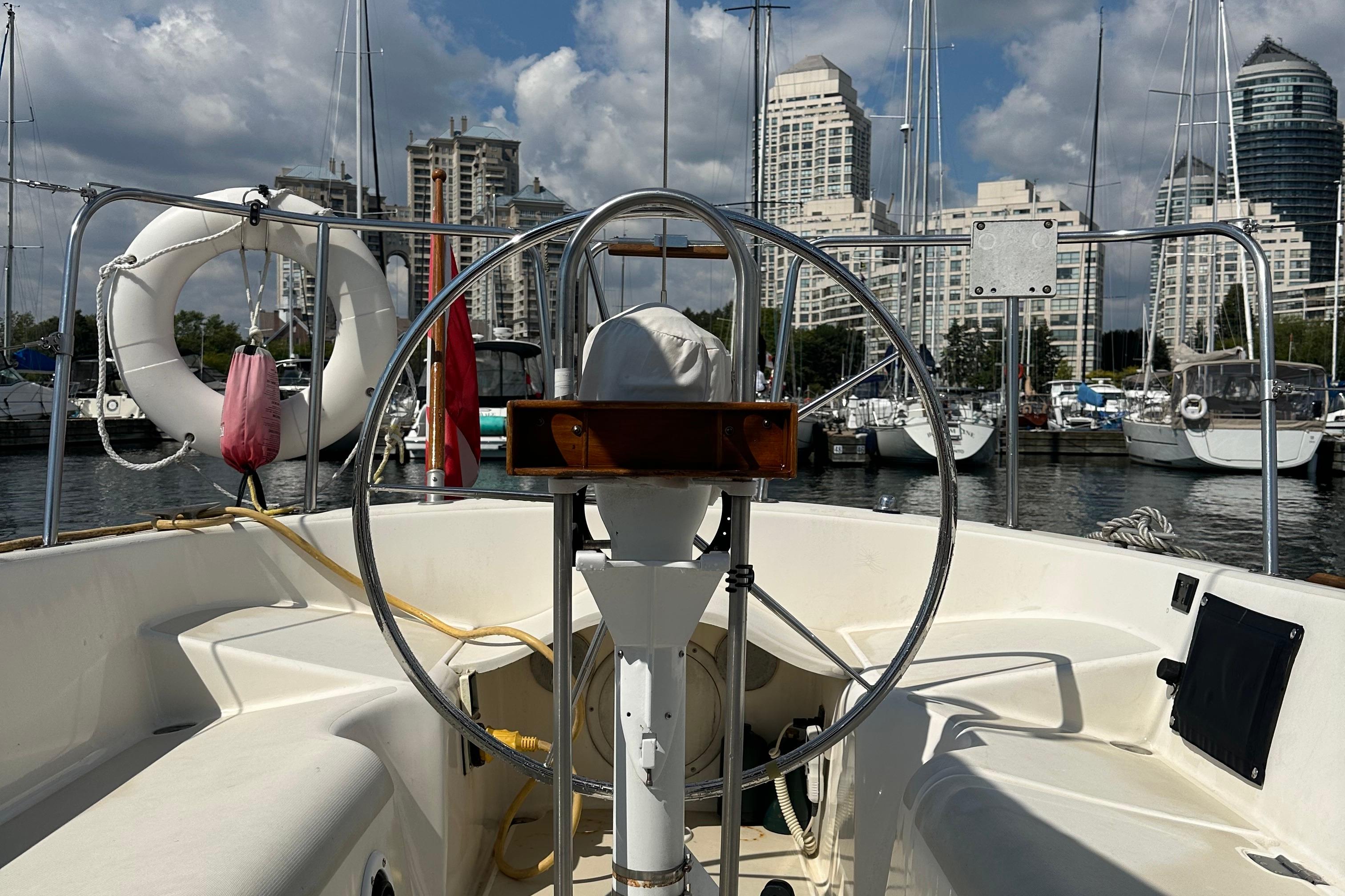 Cockpit view of 1984 Pearson 34 sailboat docked in marina with city skyline.
