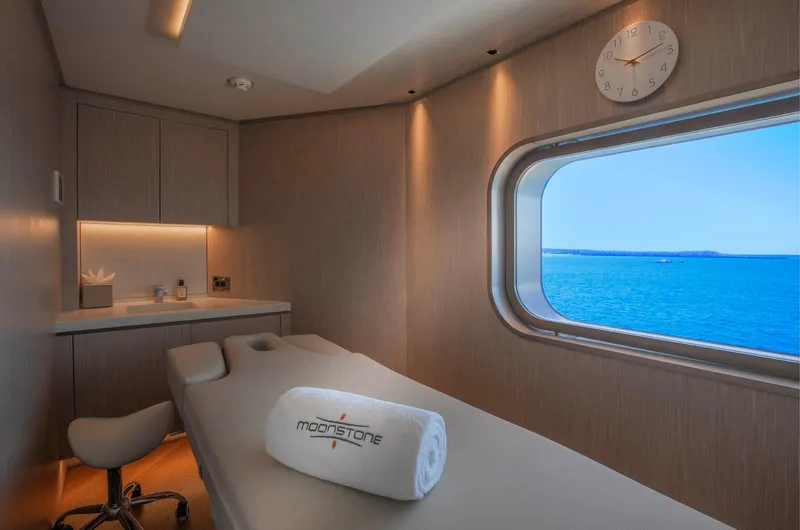 Moonstone Yacht Photos Pics Luxurious spa room on Amels 200 yacht, featuring massage table and ocean view.