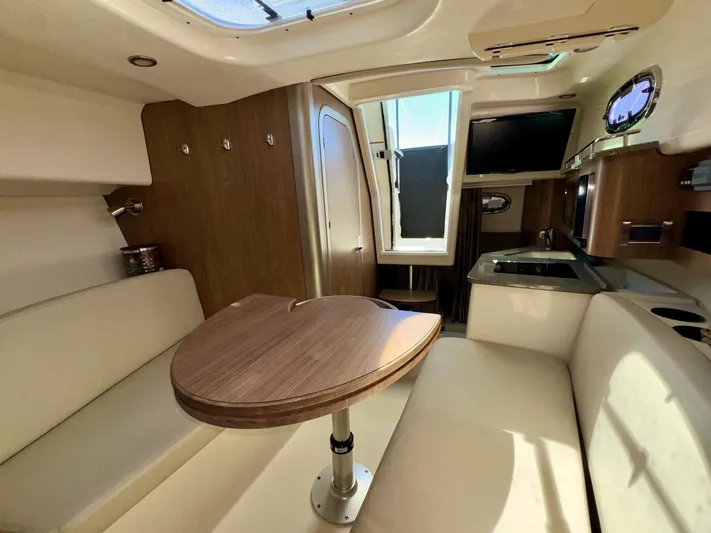  Yacht Photos Pics 2018 Boston Whaler 285 Conquest cabin interior with seating, table, and kitchenette.