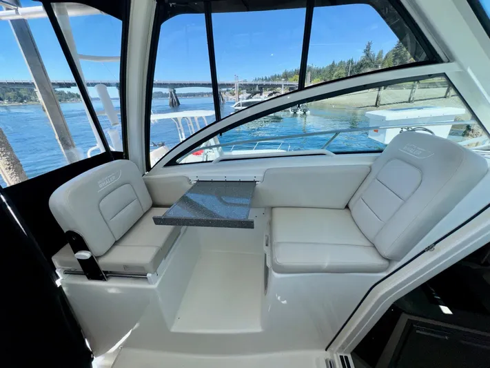  Yacht Photos Pics 2018 Boston Whaler 285 Conquest interior with seating and table, overlooking scenic waterfront.