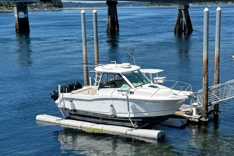  Yacht Photos Pics 2018 Boston Whaler 285 Conquest boat docked on calm water near a bridge.
