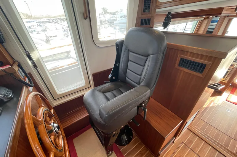 Spray Yacht Photos Pics Pilot seat and helm in 2015 Nordic Tug 39 boat interior, featuring wood accents and large windows.
