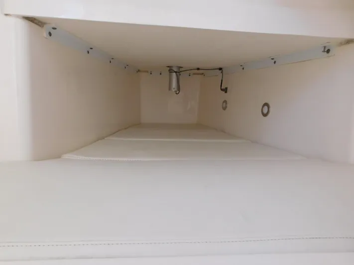  Yacht Photos Pics Storage compartment inside 2016 Everglades 355 Center Console boat, featuring white interior and metal fixtures.