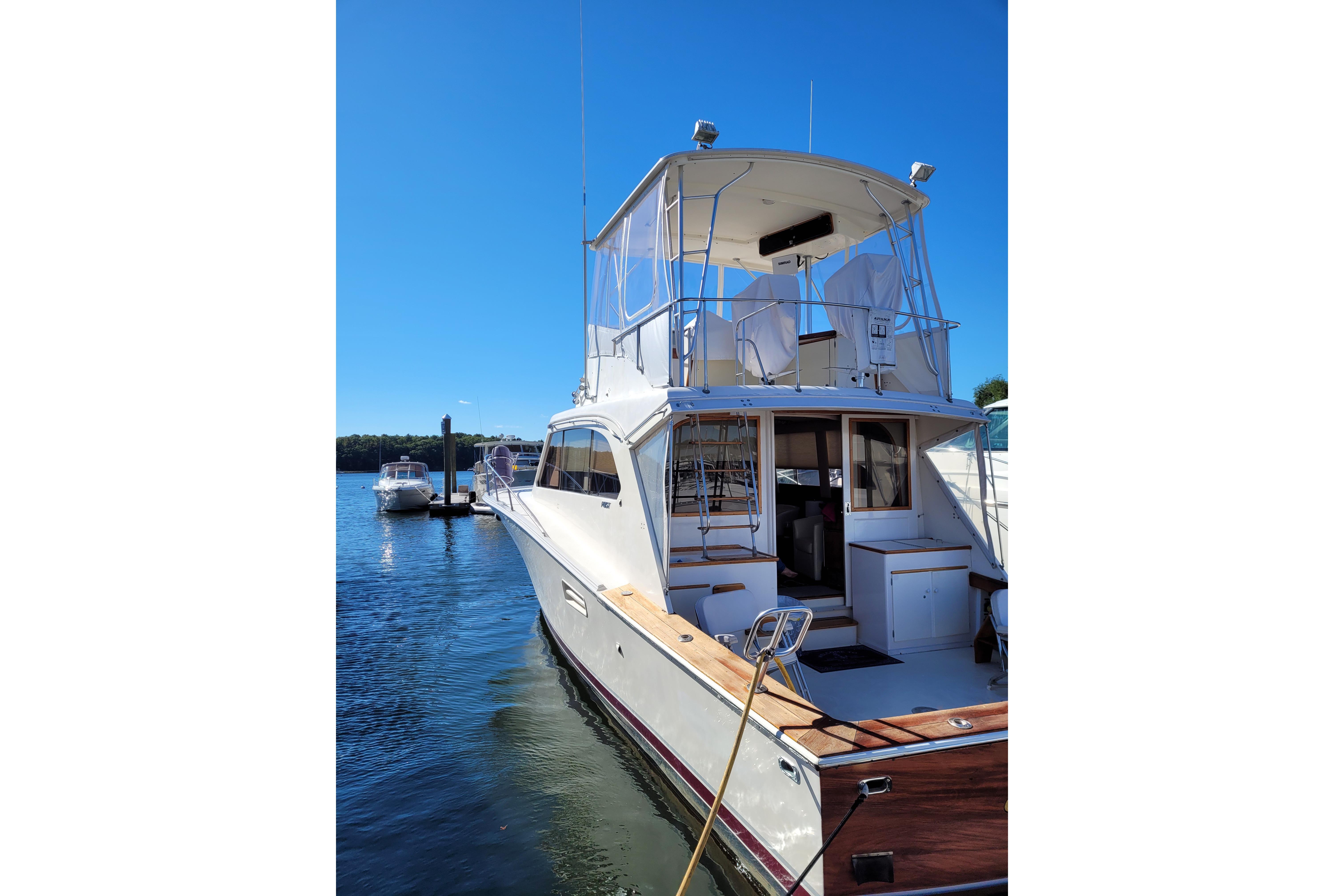 1985 Post 43 Convertible yacht docked in sunny marina, clear blue sky.