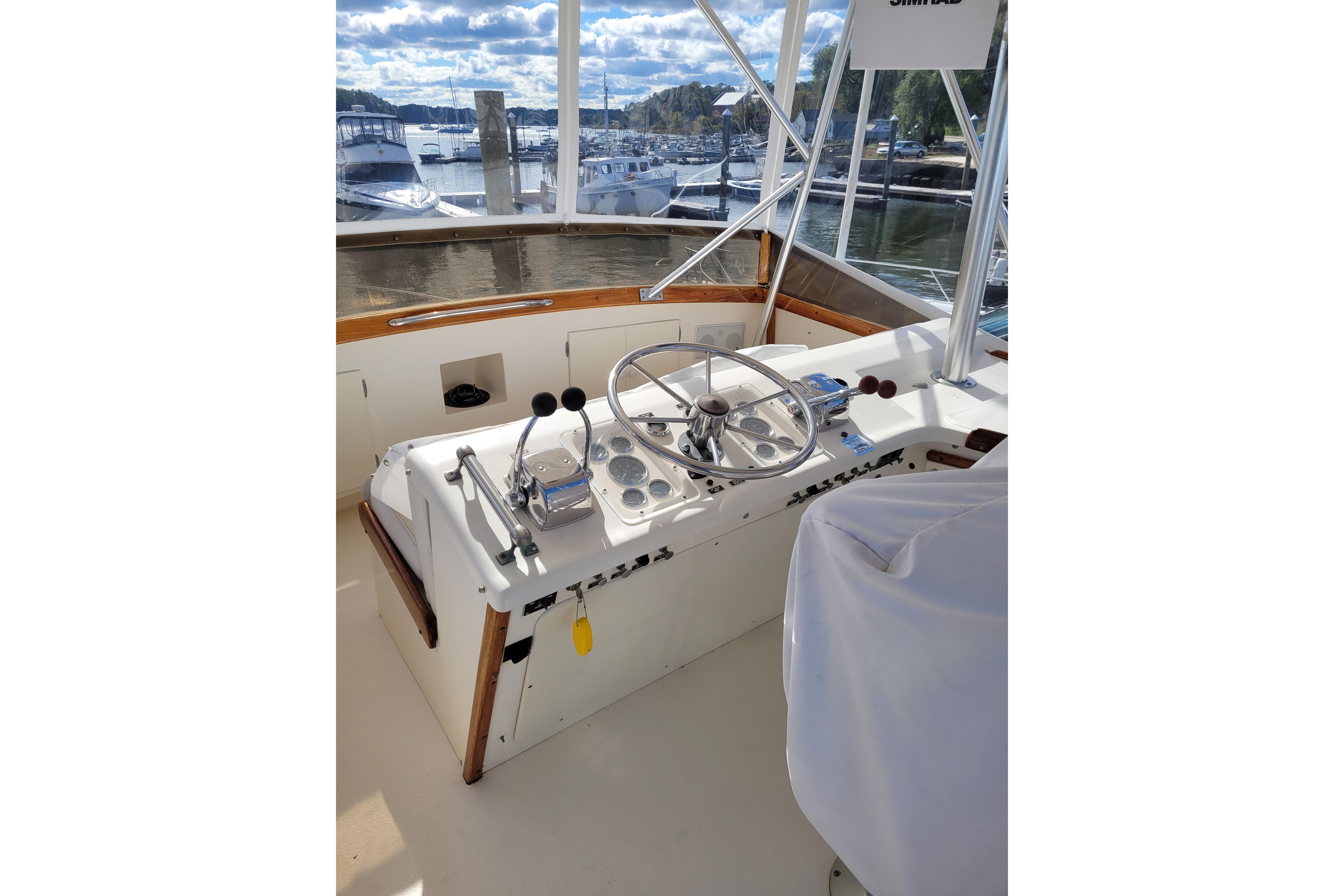 1985 Post 43 Convertible boat helm with steering wheel, controls, and marina view.