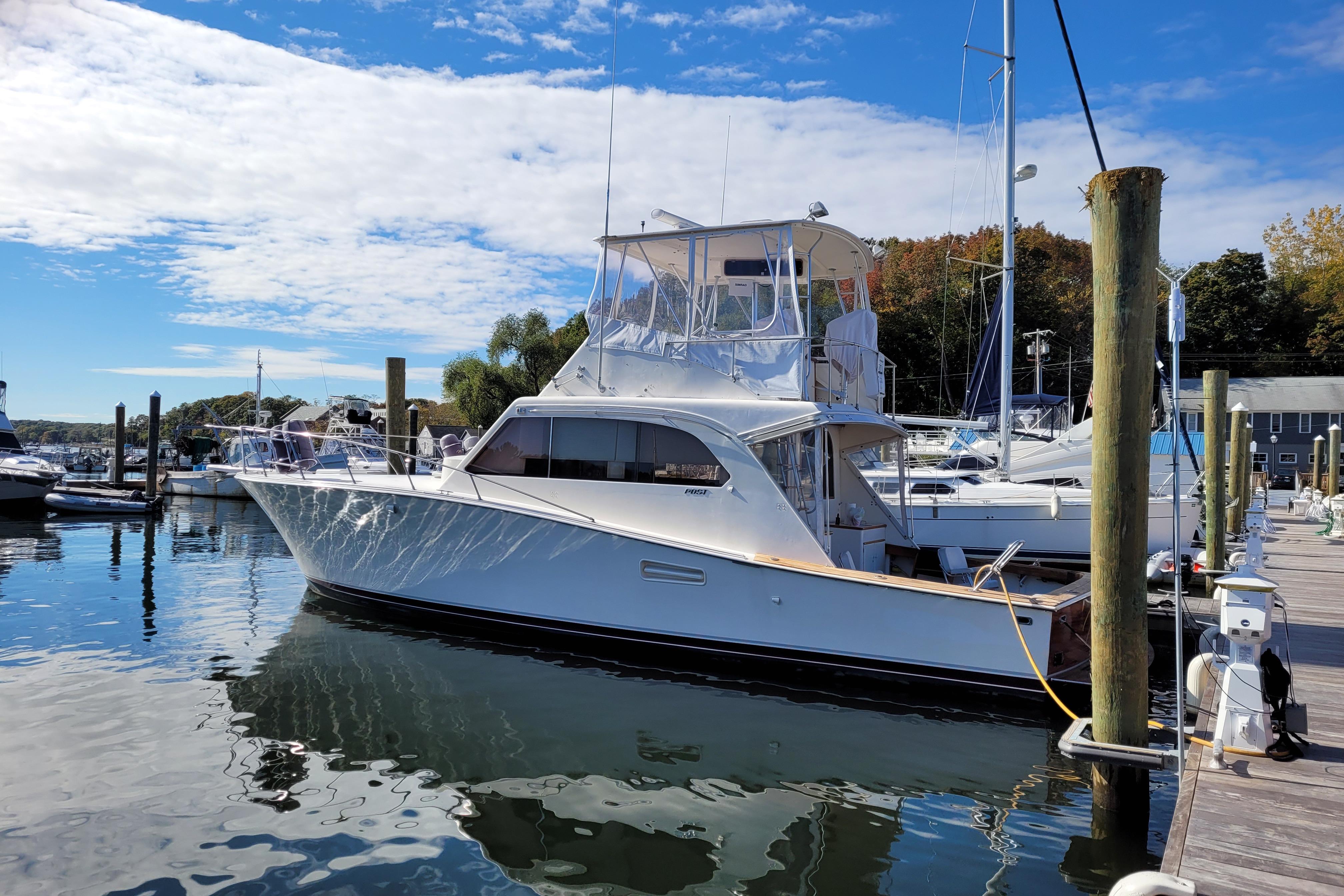 1985 Post 43 Convertible yacht docked at marina under blue sky.