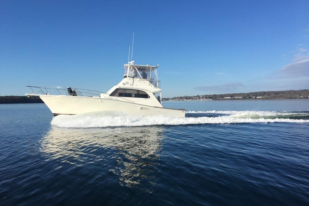 1985 Post 43 Convertible yacht cruising on calm blue waters under clear sky.