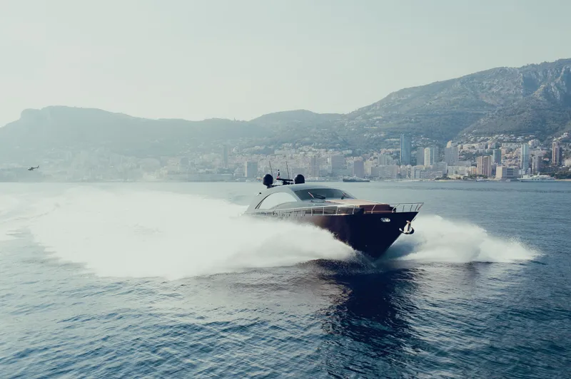 Black Rock Yacht Photos Pics Custom 77 yacht speeding on water with mountainous coastline in the background, 2008 model.