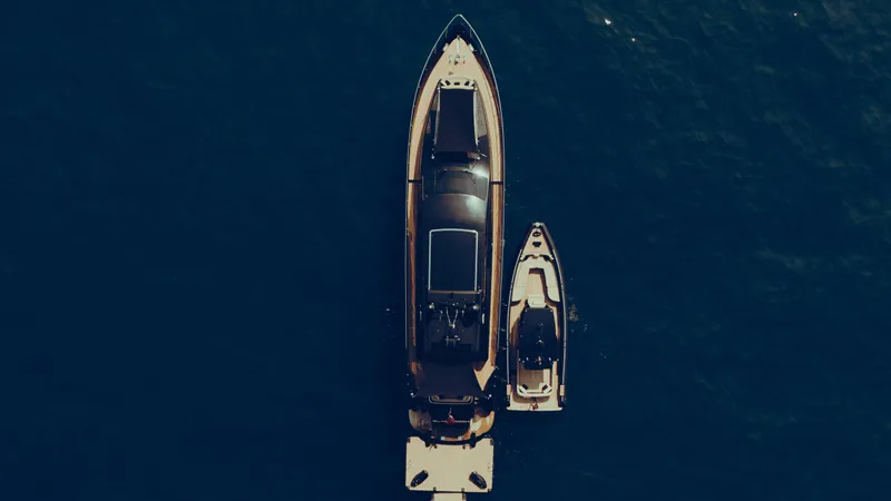 Black Rock Yacht Photos Pics Aerial view of Custom 77 yacht and smaller boat on deep blue water.