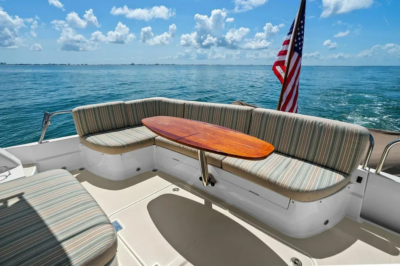 Rowe Boat Yacht Photos Pics 2018 Sabre 48 Salon Express boat with striped seating and wooden table, ocean view.