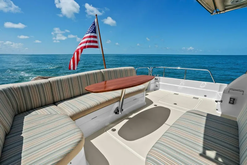 Rowe Boat Yacht Photos Pics 2018 Sabre 48 Salon Express yacht deck with seating, table, and American flag, ocean view.