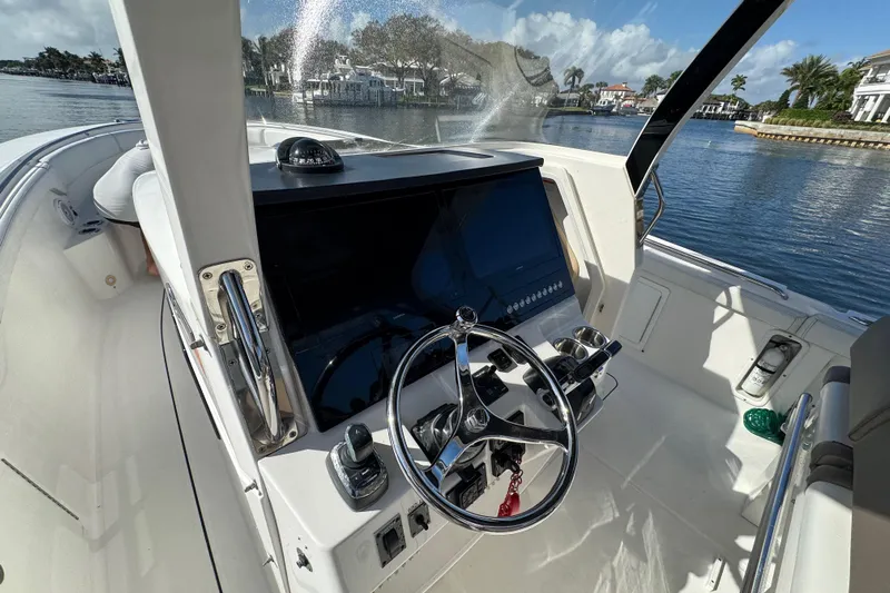  Yacht Photos Pics 2017 Edgewater 368CC boat helm with steering wheel and control panel, docked by waterfront homes.