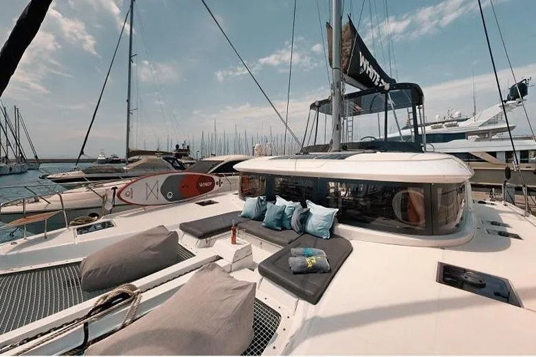 Yacht Photos Pics 2020 Lagoon 46 catamaran with sunbathing area, docked in a marina under a clear sky.