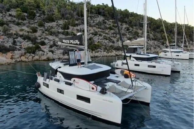  Yacht Photos Pics 2020 Lagoon 46 catamaran anchored in scenic bay with rocky shoreline.