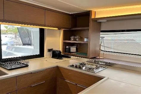  Yacht Photos Pics Modern kitchen interior of 2020 Lagoon 46 catamaran with sleek wood cabinetry and appliances.