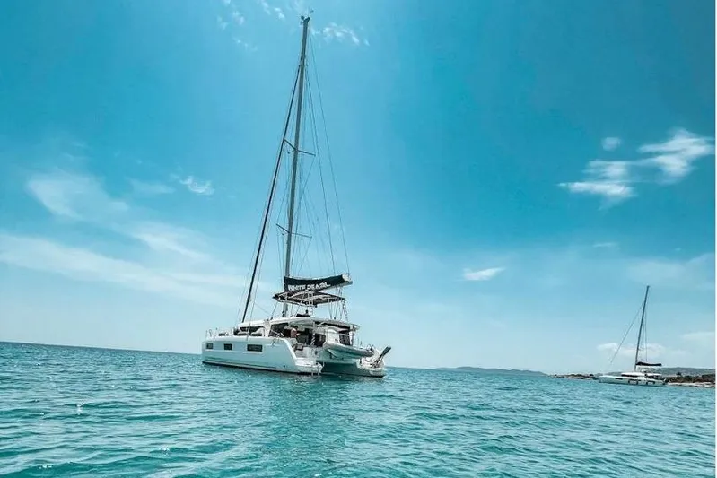  Yacht Photos Pics 2020 Lagoon 46 catamaran sailing on clear blue waters under a sunny sky.