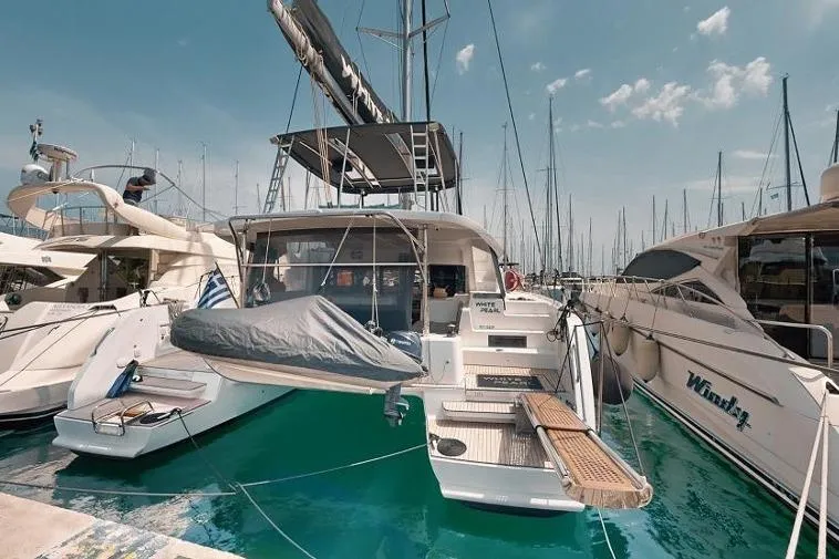  Yacht Photos Pics 2020 Lagoon 46 catamaran docked in a marina, surrounded by other boats.