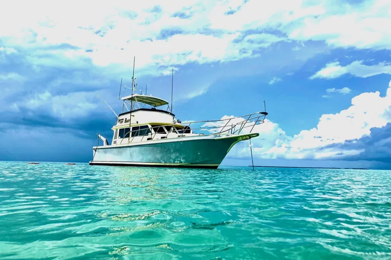 Tuff Baby Yacht Photos Pics Custom 1999 Sport Fishing boat anchored on turquoise water under a cloudy sky.