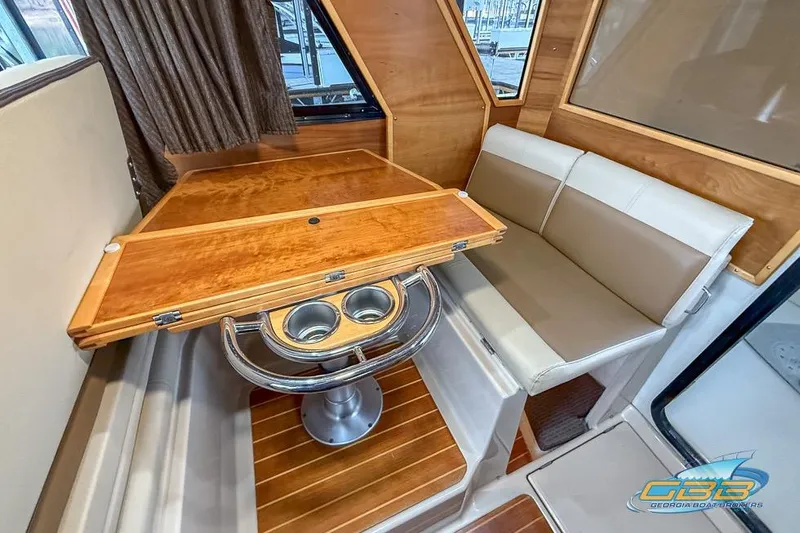  Yacht Photos Pics Interior of 2013 Cutwater C-28 boat with wooden table and cushioned seating.