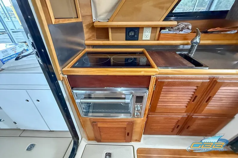  Yacht Photos Pics 2013 Cutwater C-28 boat kitchen with stove, oven, and wooden cabinetry.