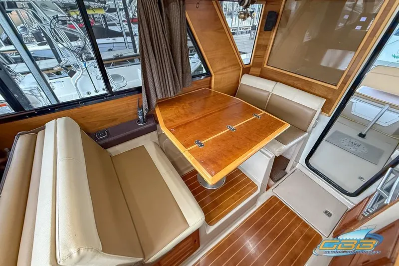  Yacht Photos Pics Interior of 2013 Cutwater C-28 boat with wooden table and beige seating.