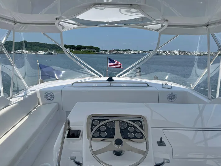 Empress Yacht Photos Pics Helm view of 2000 Hatteras 60 Convertible yacht with American flag, docked in marina.