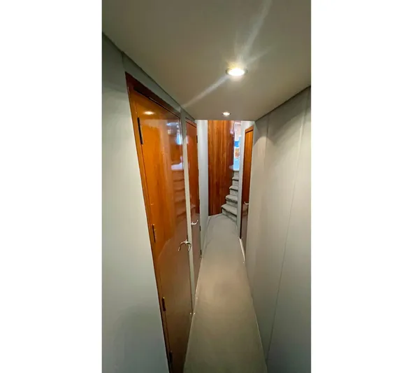 Empress Yacht Photos Pics Narrow hallway inside 2000 Hatteras 60 Convertible yacht with wooden doors and carpeted stairs.