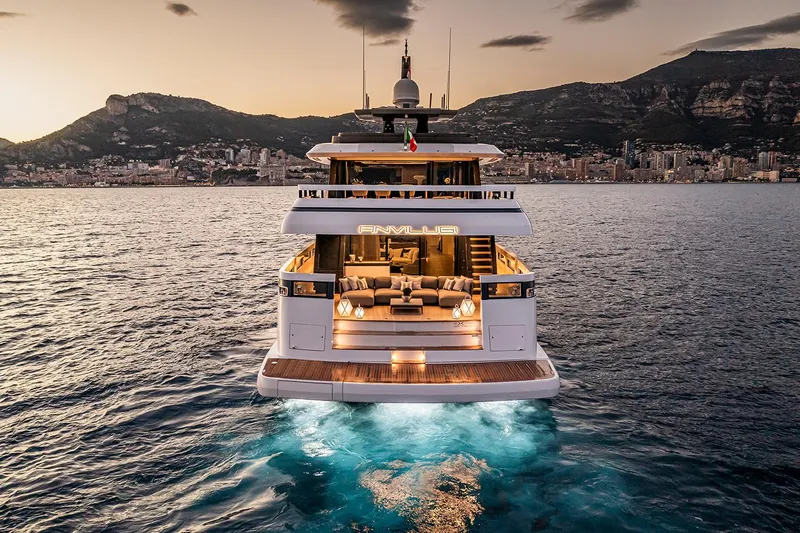 X96 Triplex Yacht Photos Pics Luxury yacht Extra X96 TRIPLEX 2025 at sunset, with illuminated water and coastal city backdrop.